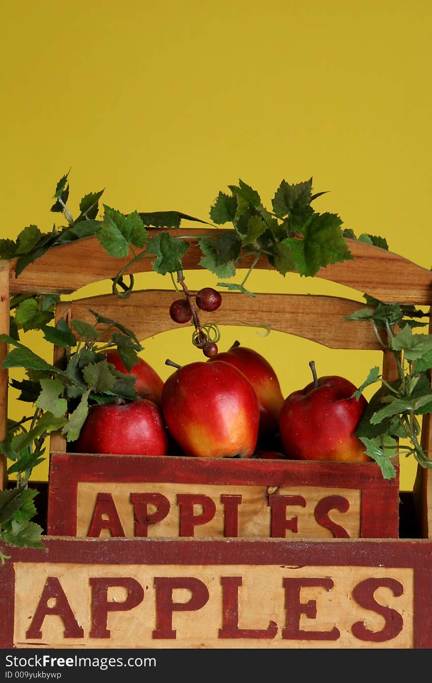 Shot of apples with ivy in a basket on yellow background. Shot of apples with ivy in a basket on yellow background