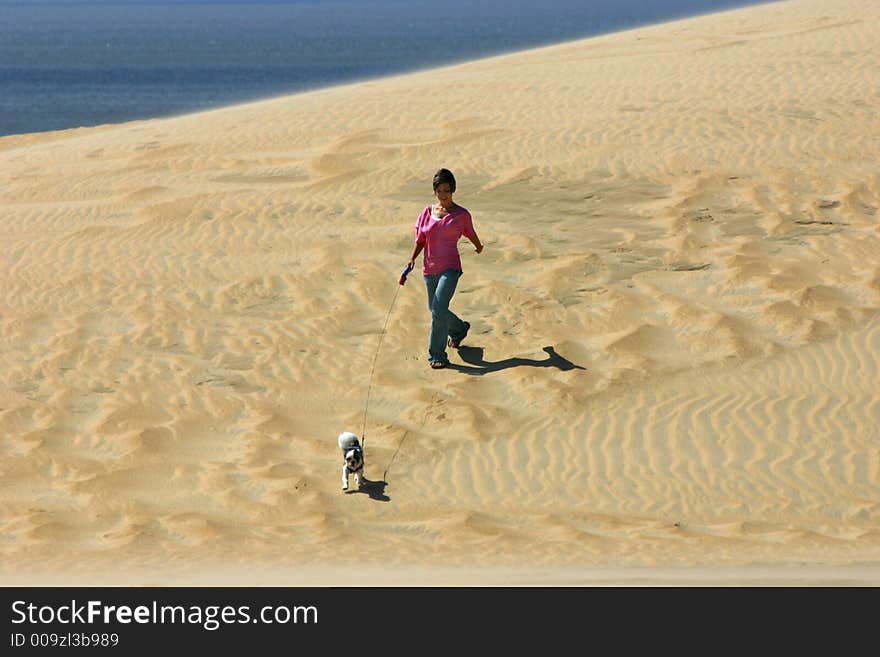 Girl walks dog on a sand dune