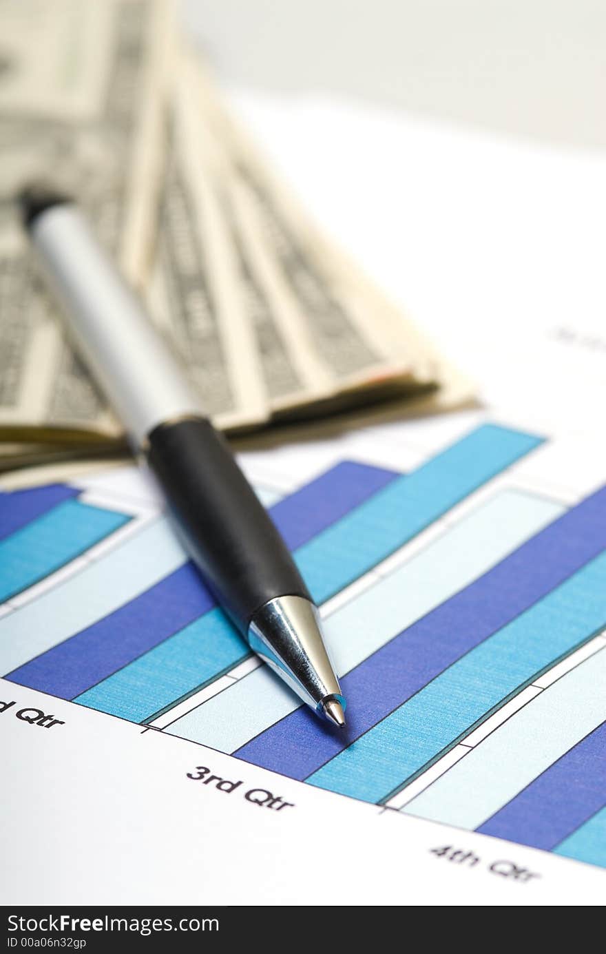 Chart with pen and cash on a desk in office. Chart with pen and cash on a desk in office