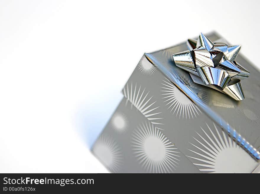 Silver wrapped present & bow isolated against white. Silver wrapped present & bow isolated against white