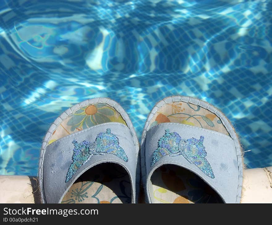 Pair of blue flip-flops by the swimming pool