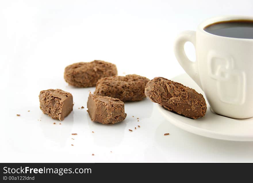 Single cup of coffee with chocolate treats on a white surface