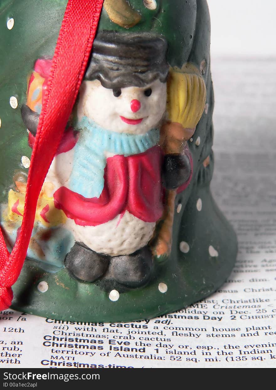 A snowan of ceramic over the word christmas. A snowan of ceramic over the word christmas