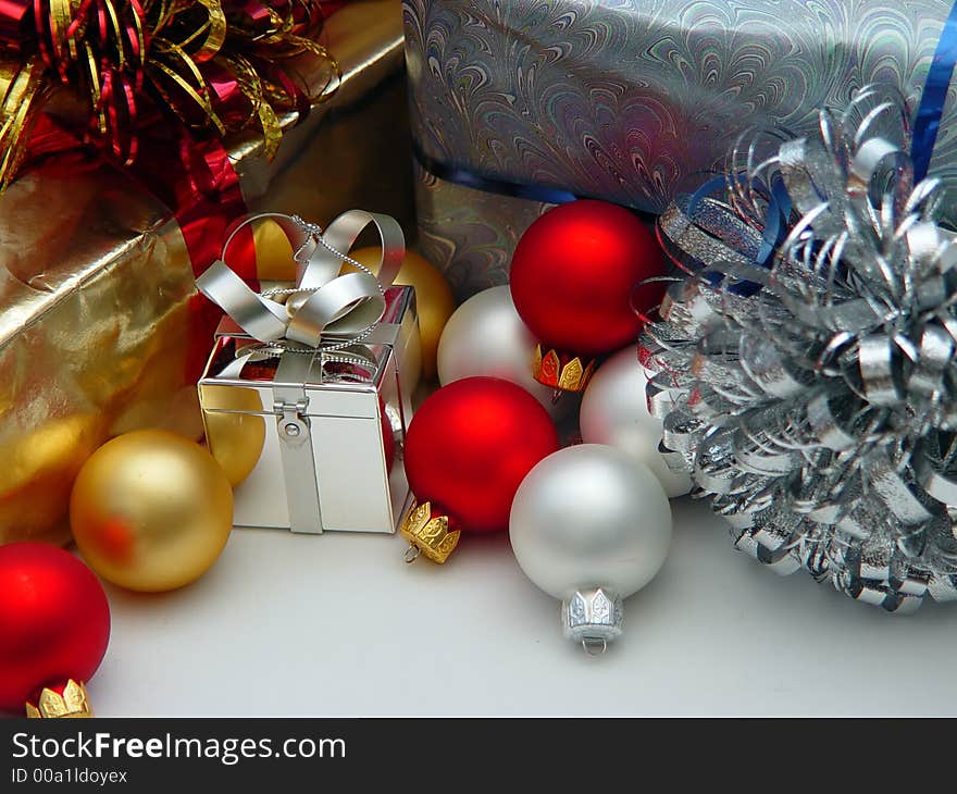 Various colored Xmas ornaments against a snowy background with gifts and bows. Various colored Xmas ornaments against a snowy background with gifts and bows.