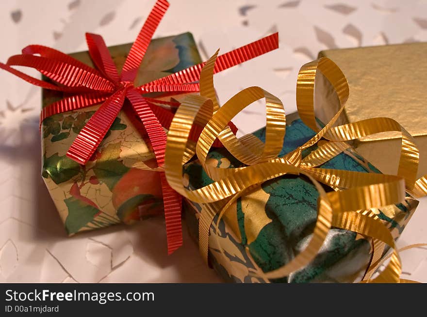 Christmas presents, gold, green and red, on white paper snowflakes. Christmas presents, gold, green and red, on white paper snowflakes.