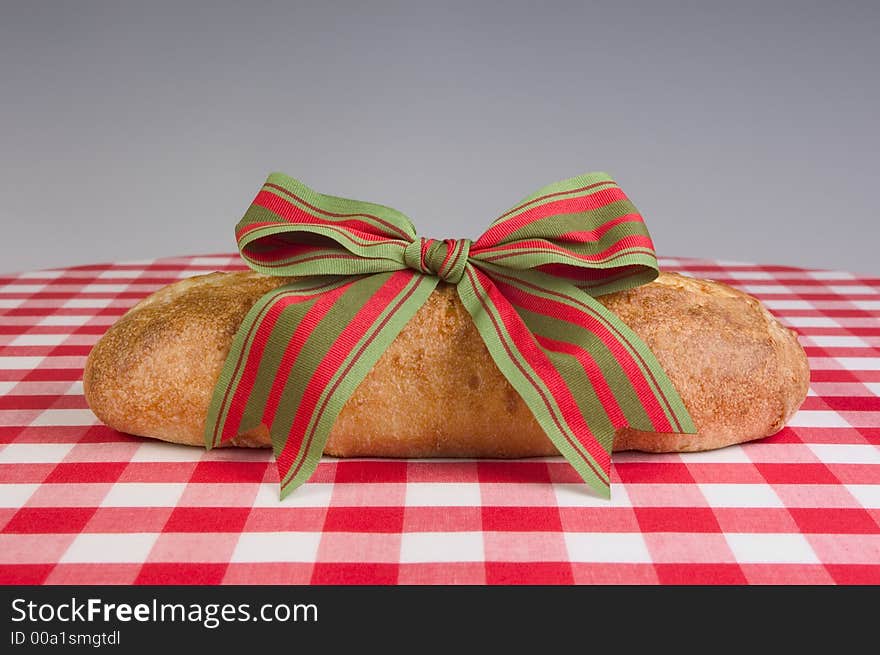 Fresh baked loaf of bread with ribbon on a red and white checkerboard cloth. Fresh baked loaf of bread with ribbon on a red and white checkerboard cloth