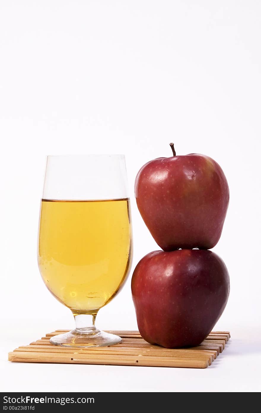 Two apples stacked beside a glass of beer