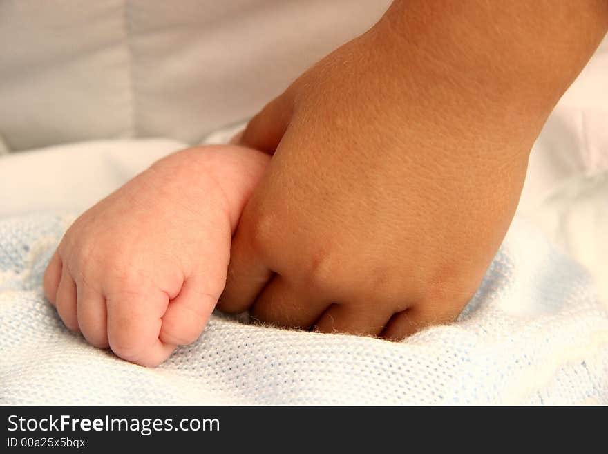 A little girl is holding the hand of her new born brother. A little girl is holding the hand of her new born brother