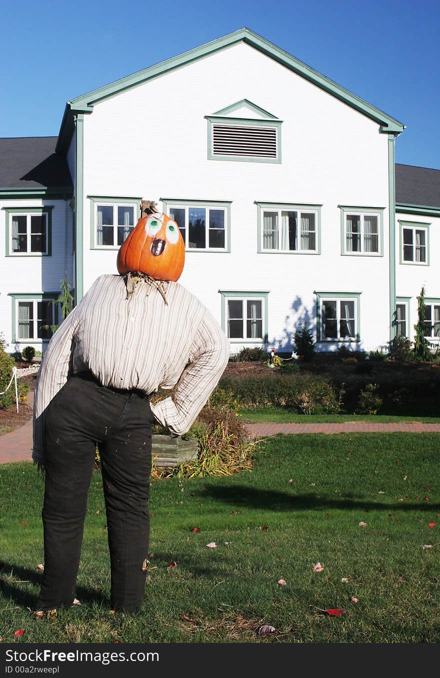 Pumpkin person in front of a house