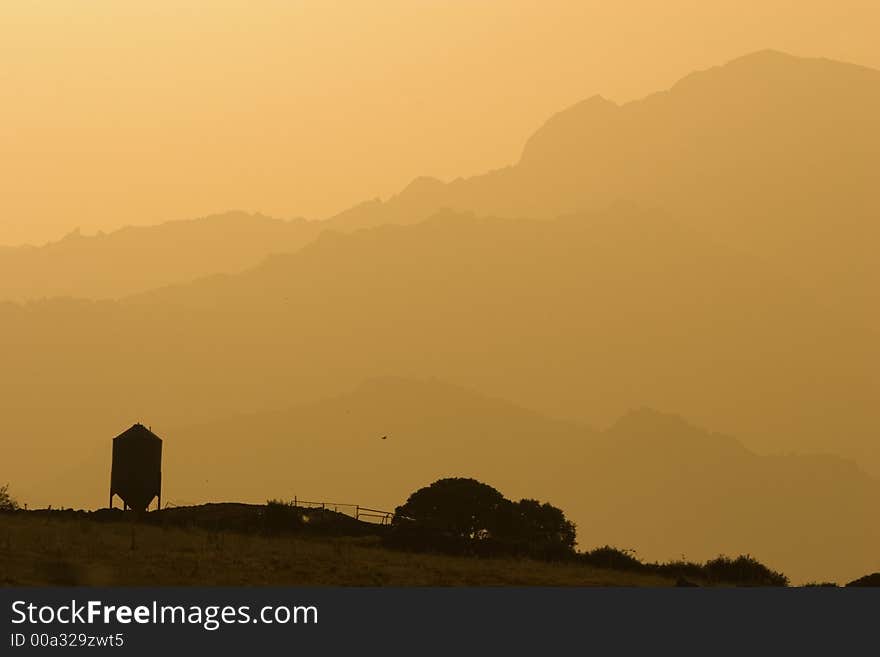 Grain Silo with the silhouette of the mountains in the backgrouns. A serene landscape. Grain Silo with the silhouette of the mountains in the backgrouns. A serene landscape