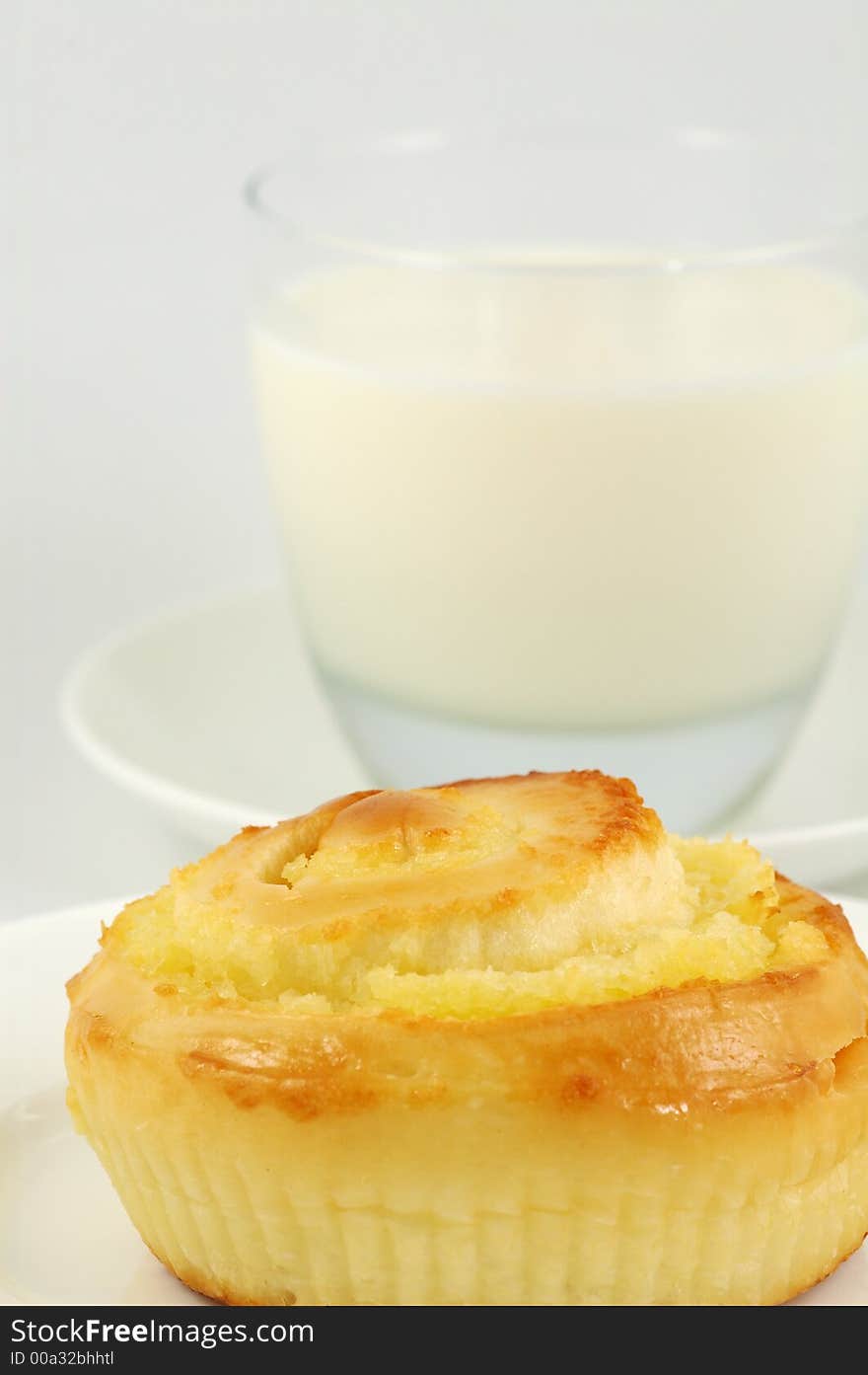 Sweet Bun on White Plate and Glass of Milk. Shallow DOF. Sweet Bun on White Plate and Glass of Milk. Shallow DOF.