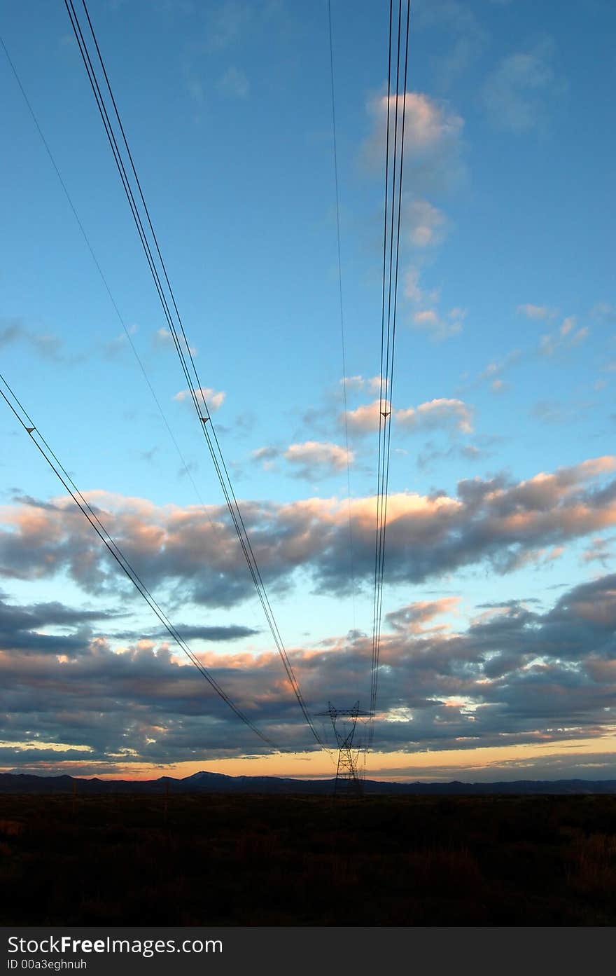 View of powerlines with sunset and clouds in background. View of powerlines with sunset and clouds in background