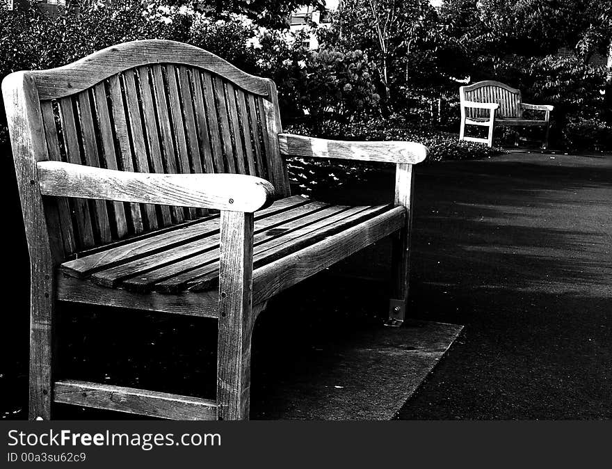 Wooden park benches along cement walking path in black and white