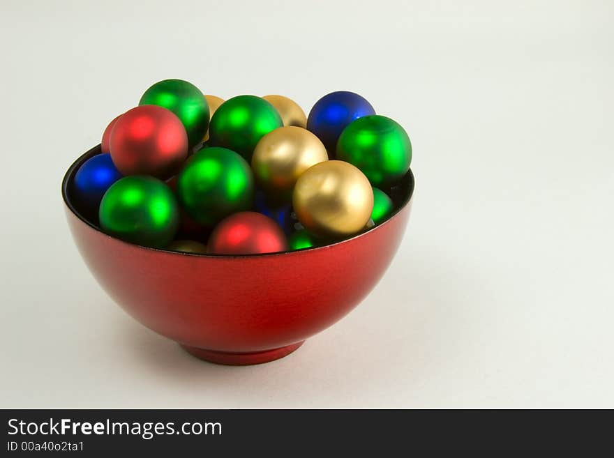 A red bowl filled with Christmas ornaments. A red bowl filled with Christmas ornaments