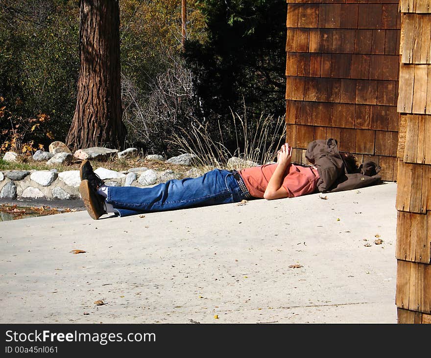 Person laying out in the sun with a coat over their head. Person laying out in the sun with a coat over their head