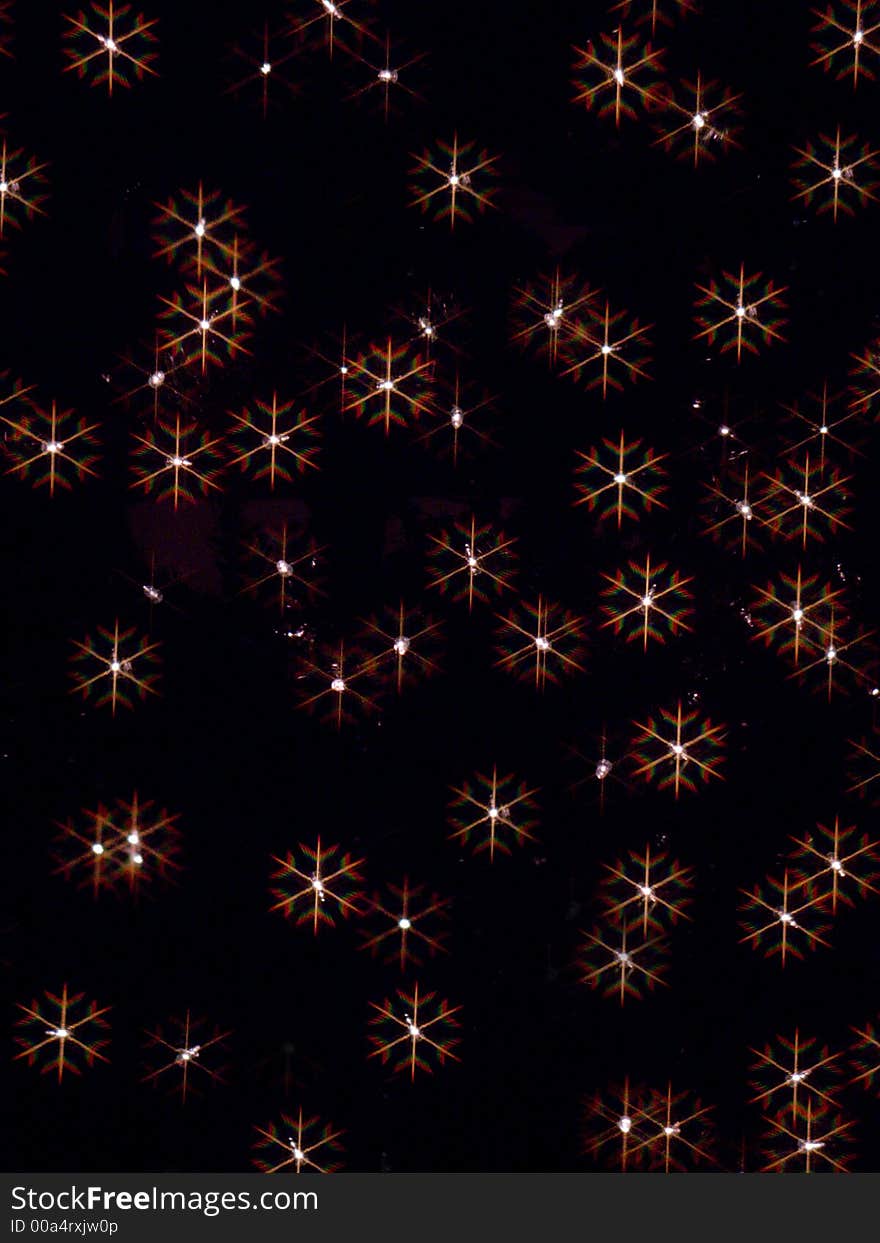 Holiday lights photographed through a snowflake filter creating prismatic snowflakes. Holiday lights photographed through a snowflake filter creating prismatic snowflakes