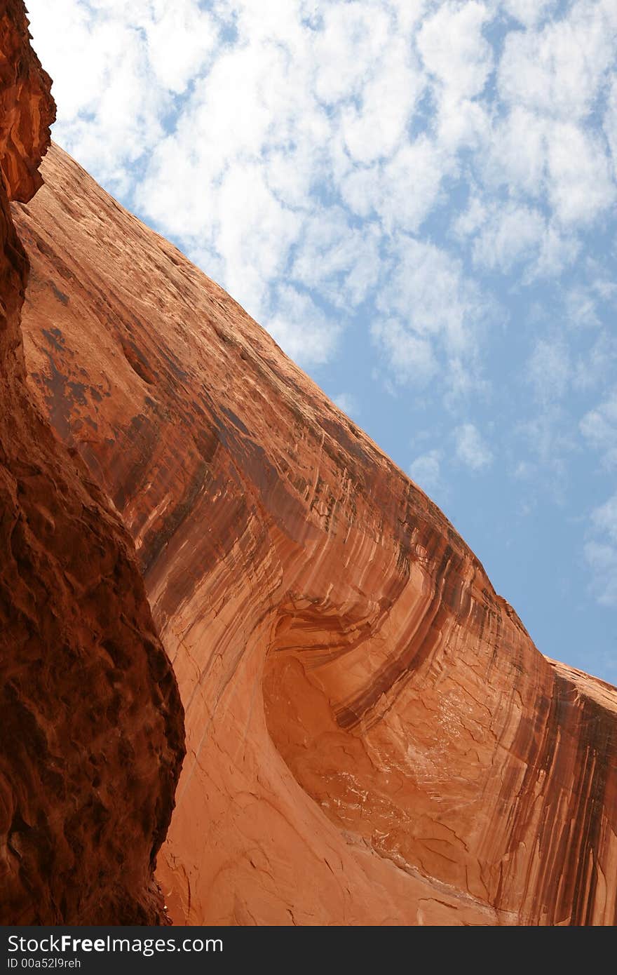 Water patterns in the face of a sandstone wall contrasting with light clouds in the sky. Lake Powell, Utah. Water patterns in the face of a sandstone wall contrasting with light clouds in the sky. Lake Powell, Utah.