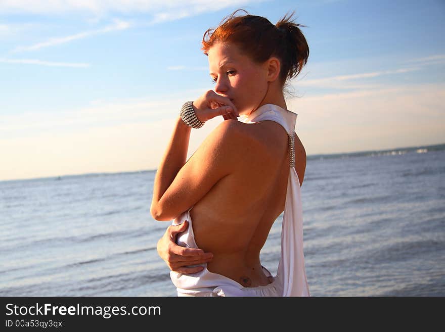 Young female dressed up, standing on a morning beach