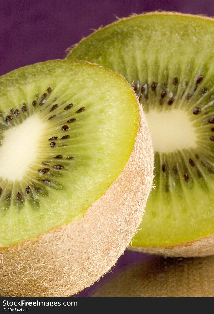 Macro of two halves of a kiwi with a purple background on mirror. Macro of two halves of a kiwi with a purple background on mirror