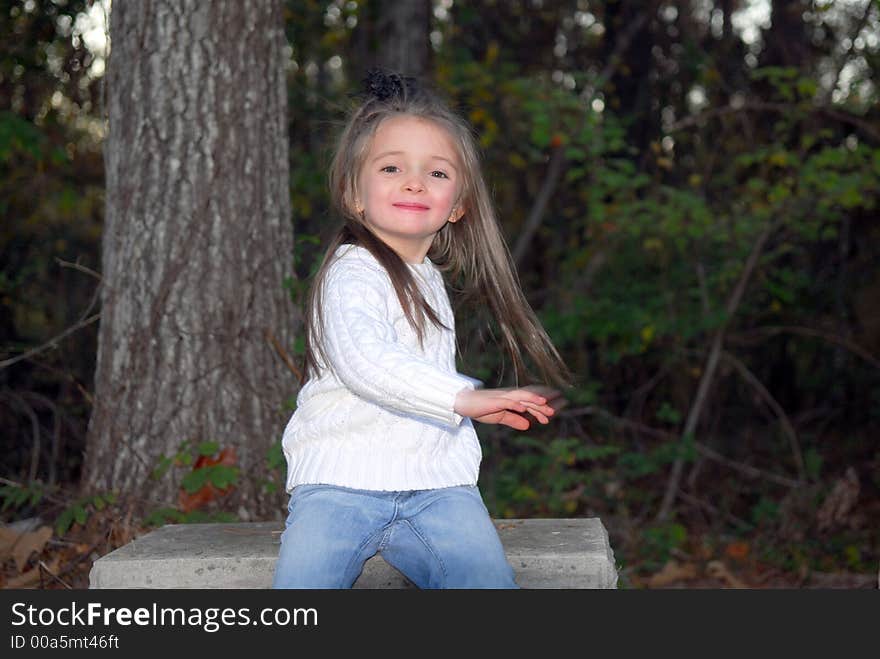 Watch Me! I can do this. A little girl having fun showing what she can do while sitting on a bench outdoors.