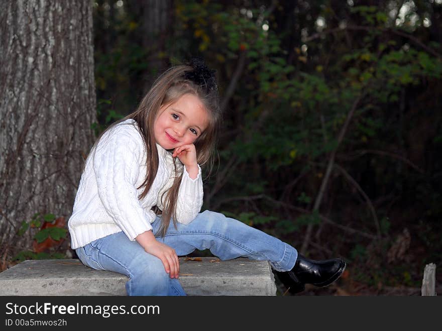 I'm adorable!  I'm just sitting here posing for this picture and I think I look sooo cute.  I'm dressed in blue jeans, a white sweater and black boots.  I have long brunette hair and brown eyes.  The setting is outdoors.