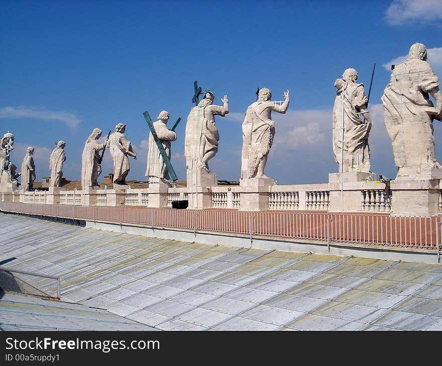 Statues of apostles looking down from the roof of St.Peter's Basilica in Vatican. Seen from behind against the blue sky. Statues of apostles looking down from the roof of St.Peter's Basilica in Vatican. Seen from behind against the blue sky.