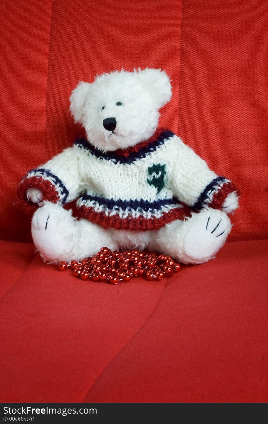 Christmas teddy bear toy sitting on a red chair