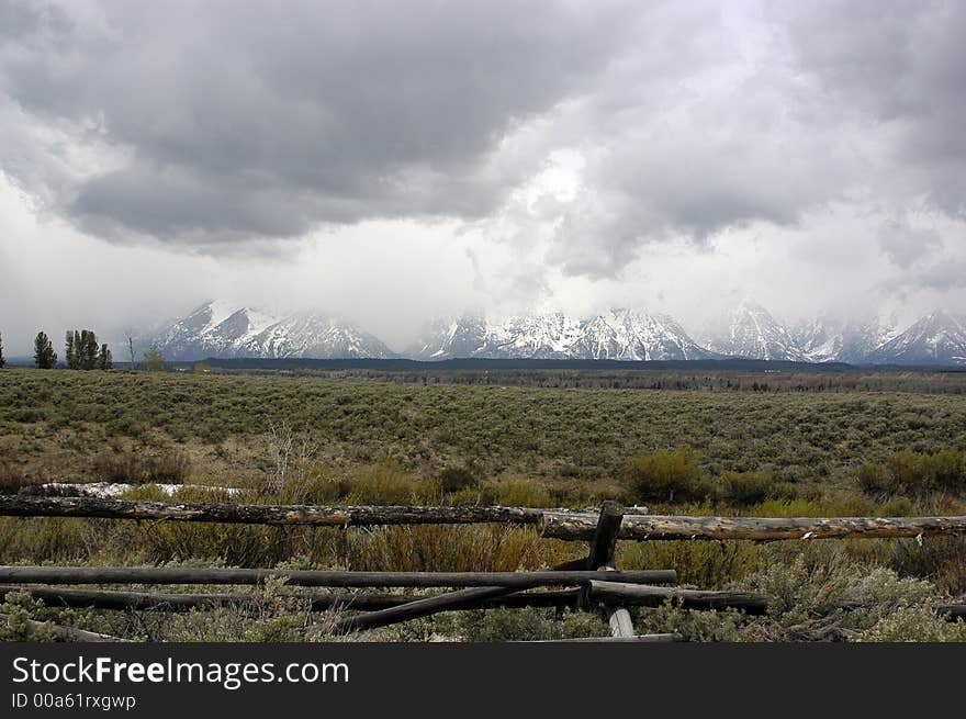 Rustic fenceline with the cloud covered Grand Tetons in the background. Rustic fenceline with the cloud covered Grand Tetons in the background.