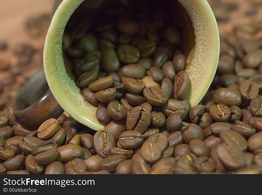 Brown cup filled with coffee beans against wooden background