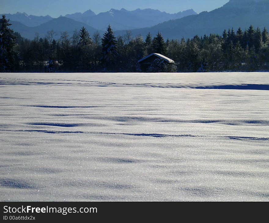 Lone Cottage in Snow Landscape with Mountain Backdrop