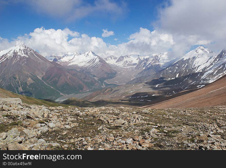 View of gorge and snowy apexes from the pass in high mountains. View of gorge and snowy apexes from the pass in high mountains