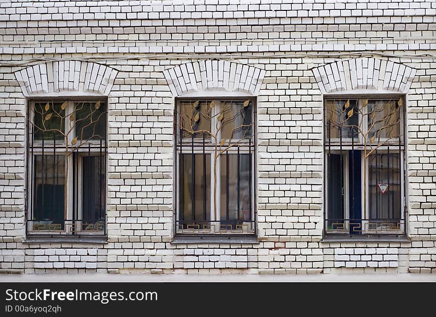 Three windows and a white brick wall