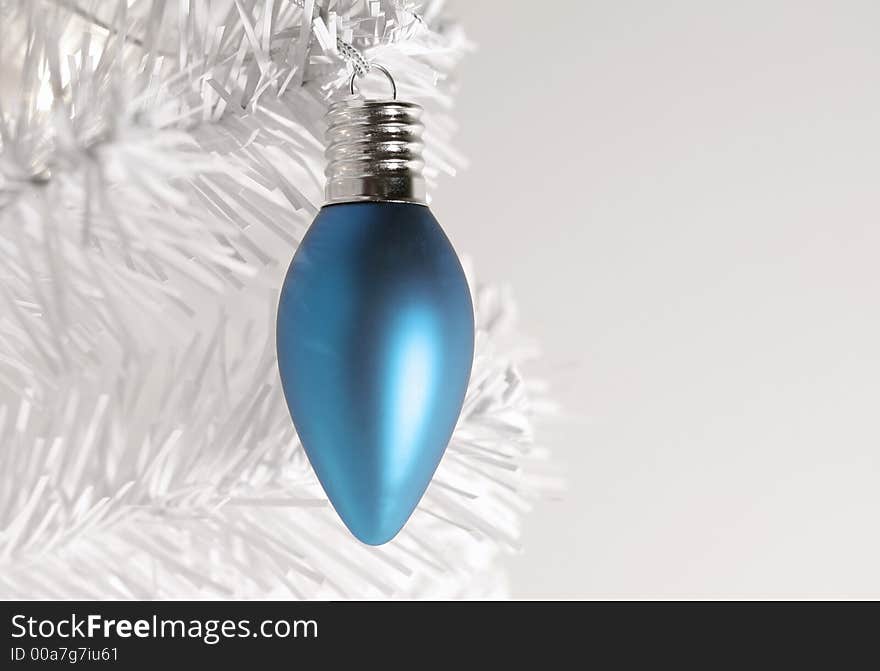 Icy blue Christmas ornament hanging from branch of modern white  artificial tree. Icy blue Christmas ornament hanging from branch of modern white  artificial tree