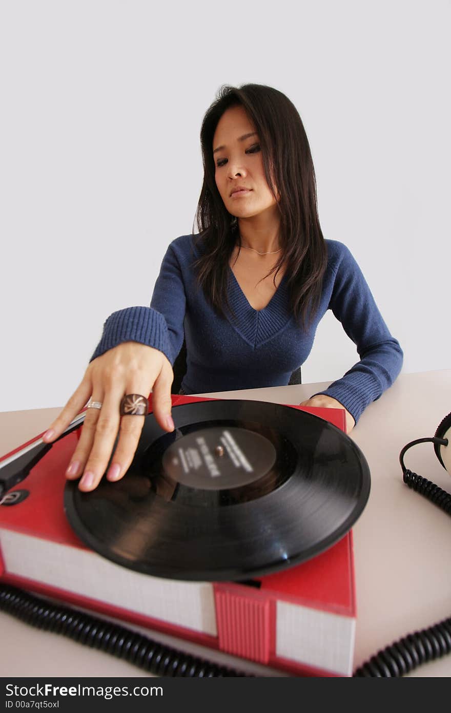 Studio shot of japanese woman looking at retro record player and headphones. Studio shot of japanese woman looking at retro record player and headphones