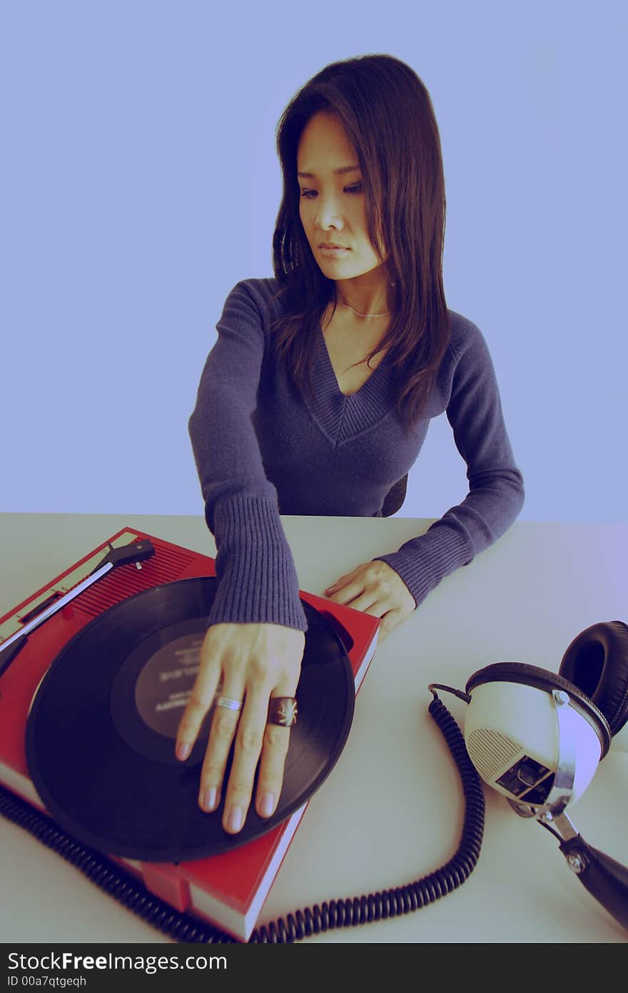 Studio shot of japanese woman looking at retro record player and headphones. Studio shot of japanese woman looking at retro record player and headphones