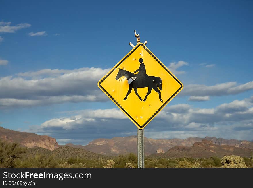 Blue sky and clouds of rural desert landscape with horse crossing sign