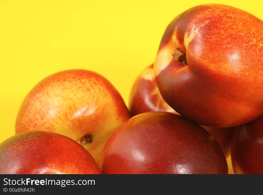 Colorful nectarines (peaches) over yellow background. Closeup. Colorful nectarines (peaches) over yellow background. Closeup.