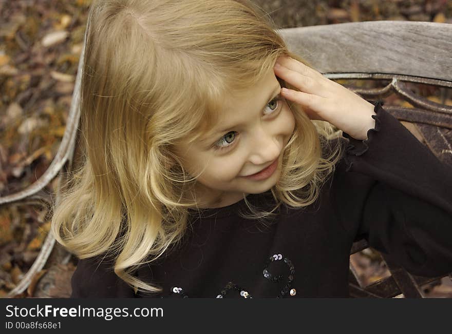 Cute little girl posing on a bench in autumn. Cute little girl posing on a bench in autumn