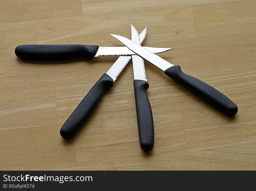 Set of four steak knives arranged against a butcher block tabletop