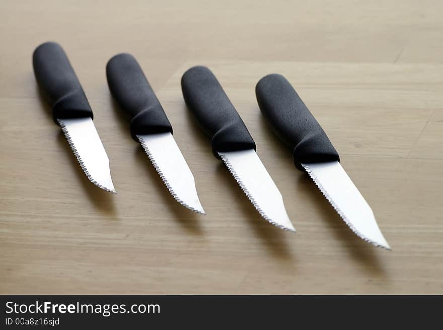 Set of four serrated steak knives against a butcher block tabletop