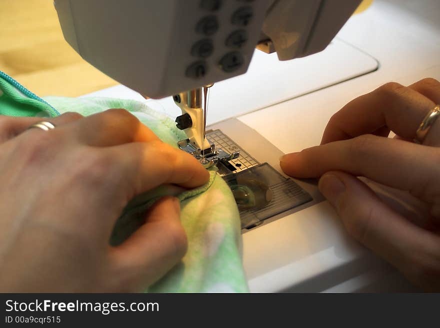 Using sewing machine. Focus on left hand´s pointer finger tip.