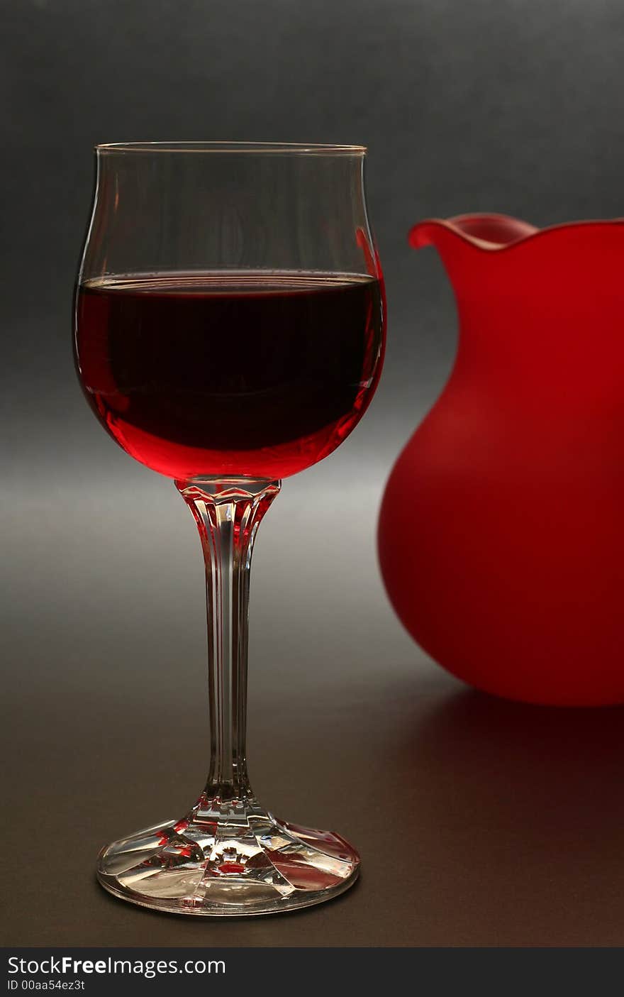 Glass of red wine with red vase in the background. Glass of red wine with red vase in the background