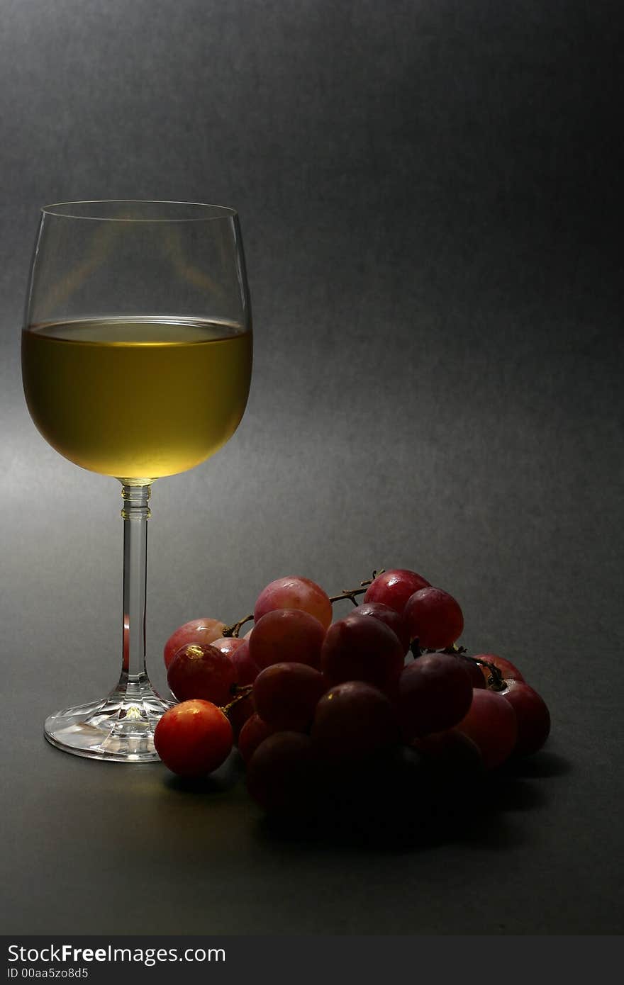 Low key image of chilled white wine with grapes on dark background