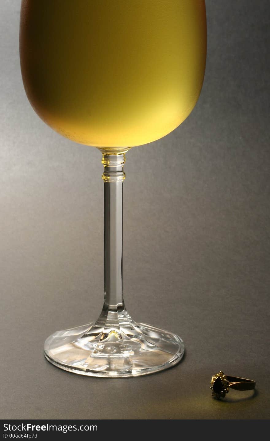 Low key image of chilled white wine with a ring placed at the bottom against dark background. Low key image of chilled white wine with a ring placed at the bottom against dark background