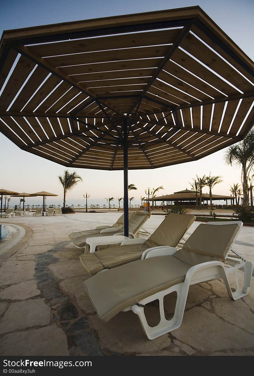 Three sunbeds under parasol near the swimming-pool