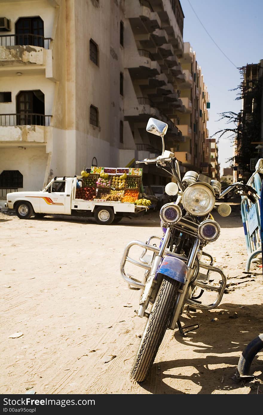 Motorbike and lorry with fruits and vegetables.