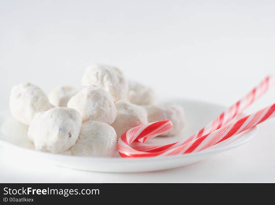 Two candy canes and round wedding cake cookies on a plate. Two candy canes and round wedding cake cookies on a plate.