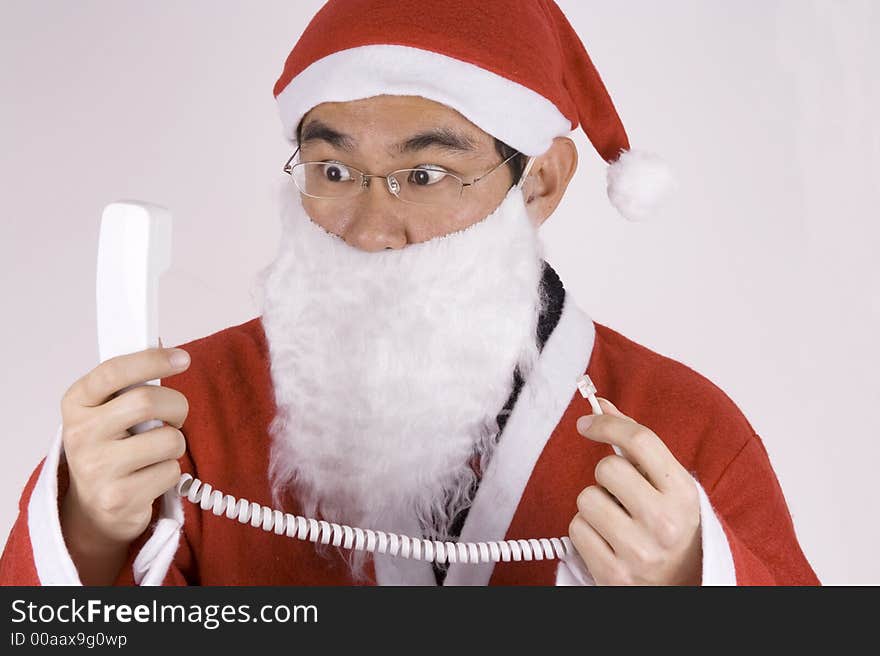 Asian Santa Claus holding a telephone receiver with expression. Asian Santa Claus holding a telephone receiver with expression.