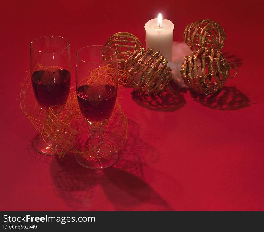 Romantic composition with wicker Christmas tree balls, candle and two glass of red wine (on red background with their shadows). Make specially some dark. Romantic composition with wicker Christmas tree balls, candle and two glass of red wine (on red background with their shadows). Make specially some dark.