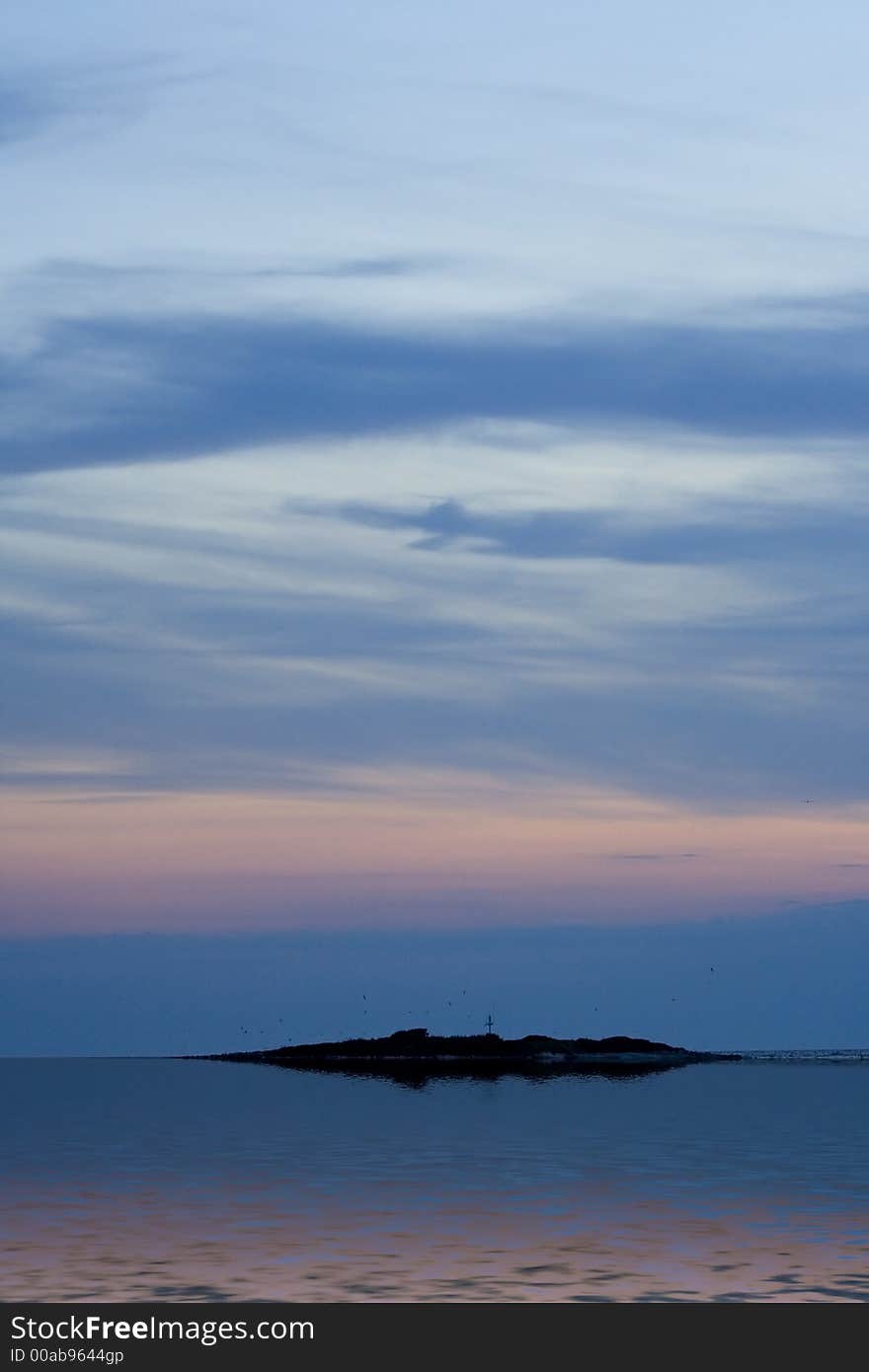 Island below sunset sky with reflection